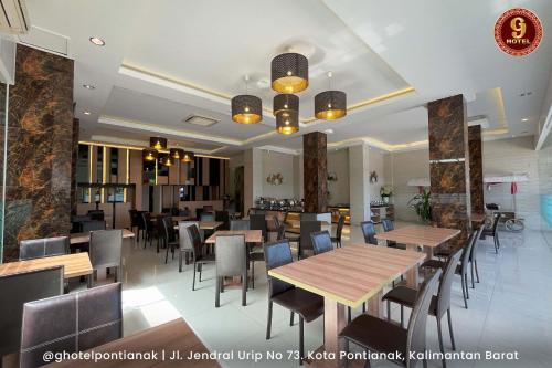 un restaurante con mesas de madera y sillas en una habitación en G-Hotel Pontianak, en Pontianak