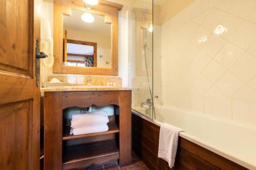 une salle de bain avec un lavabo, une baignoire et un miroir dans l'établissement Résidence Les Arcs 1950 Le Village - maeva Home - Appartement 3 Pièces 6 Personnes - Prestige MAE-4044, à Bourg-Saint-Maurice