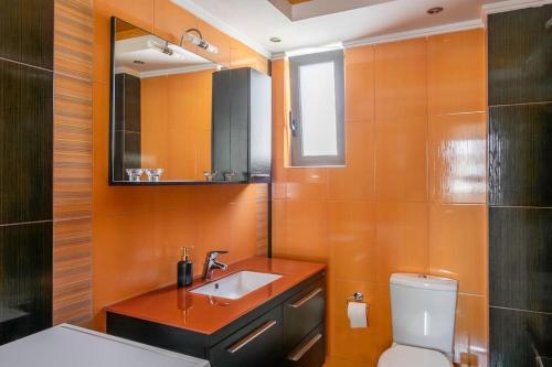 y baño con lavabo, aseo y espejo. en Comfort 1BR apt with amazing balcony at Piraeus, en Pireo