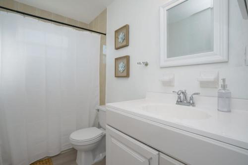 a white bathroom with a sink and a toilet at Blue Door Duplex Renovated Parking and Designed in Cutler Bay
