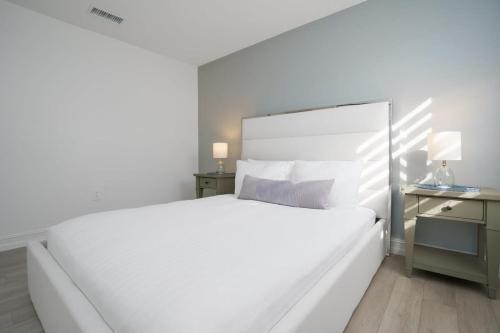 a white bedroom with a large white bed and a desk at Blue Door Duplex Renovated Parking and Designed in Cutler Bay