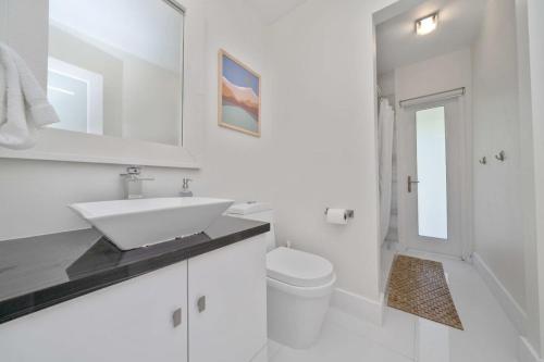 a white bathroom with a sink and a toilet at Boho House - Stylist Home with Parking and large Yard in Miami
