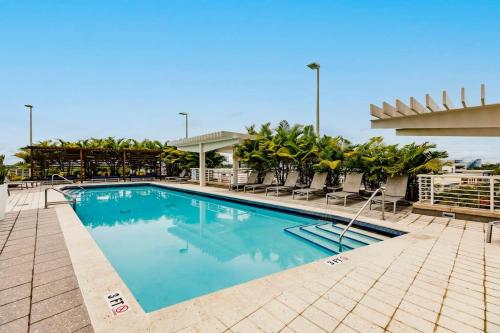 a large swimming pool with chairs and trees in a building at Urban Retreat - Location Pool Gym & Parking in Miami