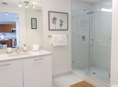 a white bathroom with a shower and a sink at Palm Place Heart of Miami with Parking Pool and Gym in Miami