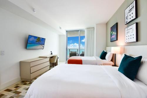 een hotelkamer met 2 bedden, een bureau en een raam bij Luxe Stay at Hyde Resort -Oceanfront & Amenities in Hollywood