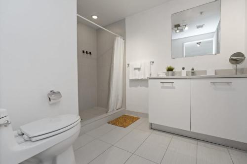 een witte badkamer met een toilet en een douche bij City Condo in Midtown Wynwood with pool and parking in Miami