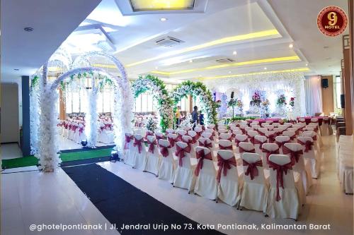 um salão de banquetes com fileiras de mesas e cadeiras em G-Hotel Pontianak em Pontianak