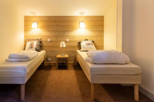 two beds in a room with a wooden wall at Résidence Plagne Lauze - maeva Home - Appartement 3 Pièces 7 Personnes - Pr 44 in Mâcot La Plagne