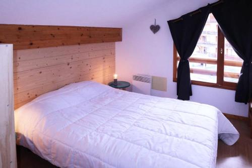 ein Schlafzimmer mit einem großen weißen Bett und einem Fenster in der Unterkunft Résidence Parc Des Airelles - 2 Pièces pour 8 Personnes 251 in Les Orres