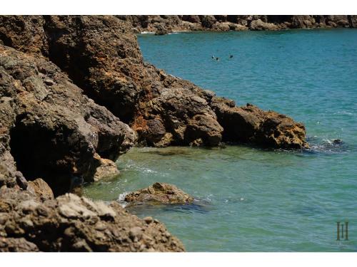 two people swimming in the water near some rocks at Cit'Hotel Imperial in Sète