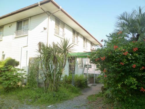 a white house with plants in front of it at Pension Flora in Tateyama