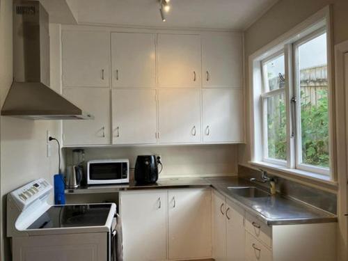 a kitchen with white cabinets and a sink and a microwave at Wellington single bedroom in Wellington