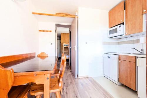 une petite cuisine avec une table et des chaises en bois dans l'établissement Résidence Les Mélèzes - maeva Home - 2 Pièces 6 Personnes - Confort MAE-2144, à Huez