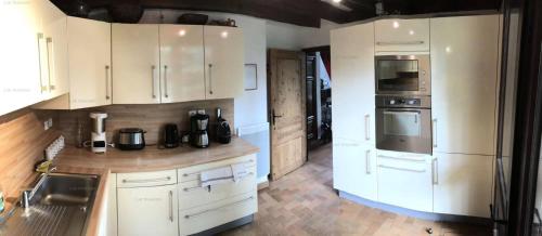 uma grande cozinha com armários e electrodomésticos brancos em Résidence Chal. Les Chandelles - Chalets pour 11 Personnes 521 em Les Orres