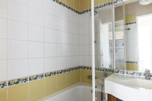 uma casa de banho com uma banheira, um lavatório e um espelho. em Résidence Le Thabor - maeva Home - Appartement 2 Pièces 5 Personnes - Sél 794 em Le Désert