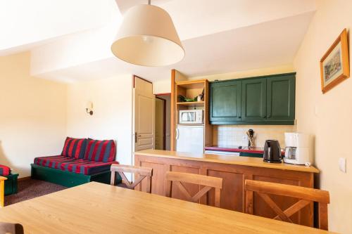 une cuisine avec des armoires vertes, une table et des chaises dans l'établissement Résidence L'Alpaga - maeva Home - Appartement 2 Pièces 7 Personnes - Confort MAE-9874, à La Salle Les Alpes