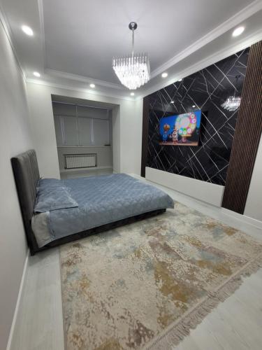 1 dormitorio con 1 cama y TV en la pared en Квартира 1- комнатная, en Aktobe