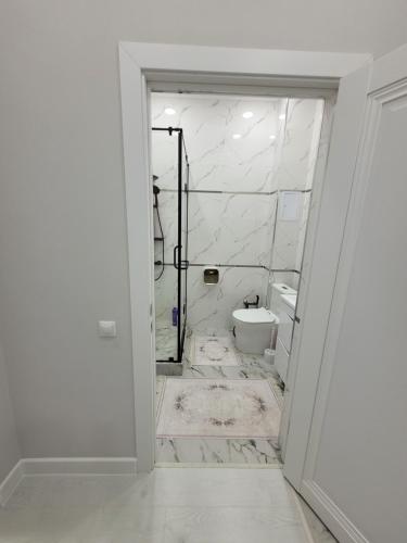 Baño blanco con aseo y lavamanos en Квартира 1- комнатная, en Aktobe