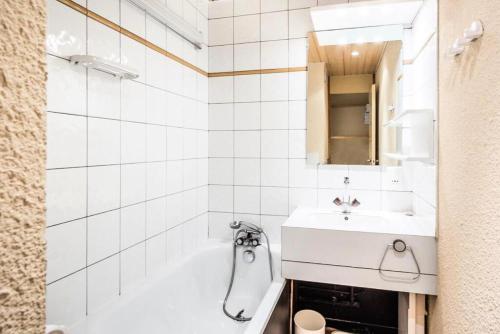 La salle de bains blanche est pourvue d'un lavabo et d'une baignoire. dans l'établissement Résidence Les Chalets des Arolles - maeva Home - Studio 5 Personnes - Sélection MAE-0004, à La Plagne Tarentaise