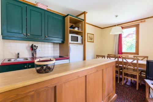une cuisine avec des placards verts et un comptoir dans l'établissement Résidence L'Alpaga - maeva Home - Appartement 2 Pièces 5 Personnes - Budget MAE-9994, à La Salle Les Alpes