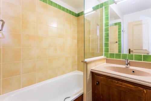 une salle de bain avec une baignoire et un lavabo dans l'établissement Résidence L'Alpaga - maeva Home - Appartement 2 Pièces 5 Personnes - Budget MAE-9994, à La Salle Les Alpes