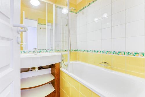 une salle de bain avec une baignoire et un lavabo dans l'établissement Résidence Le Thabor - maeva Home - Appartement 2 Pièces 5 Personnes - Confort MAE-6374, à Le Désert