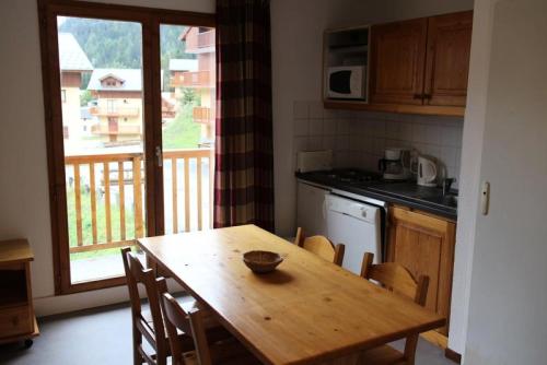 una cocina con una mesa de madera con sillas y una ventana en Les Chalets D'arrondaz - 3 Pièces pour 6 Personnes 38, en Modane