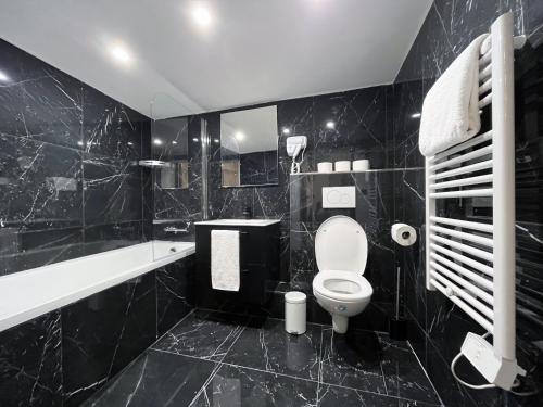 La salle de bains est pourvue de carrelage noir, de toilettes et d'un lavabo. dans l'établissement Urban Flat 175 - Loft St Denis, à Paris
