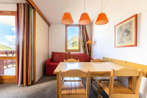 un salon avec une table et un canapé rouge dans l'établissement Résidence Les Chalets des Arolles - maeva Home - Studio 4 Personnes - Confort MAE-0024, à La Plagne Tarentaise