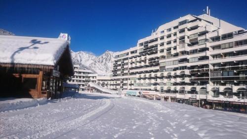 a snow covered street in front of a large building at Résidence Podium - Studio pour 3 Personnes 974 in Les Prés