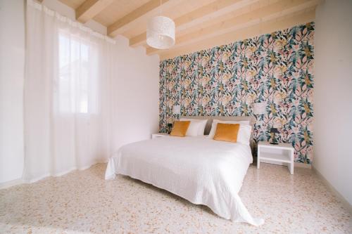 a bedroom with a white bed and a floral wallpaper at Locanda Golf Musella in San Martino Buon Albergo