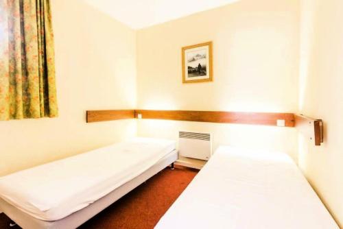 une chambre avec deux lits et une fenêtre dans l'établissement Résidences quartier Charmettoger - maeva Home - Appartement 2 Pièces 5 Personnes - Budget MAE-9914, à Arc 1800