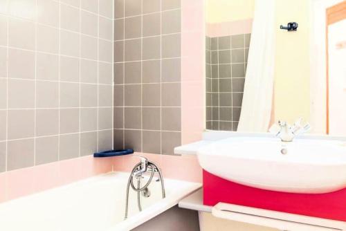 La salle de bains est pourvue d'un lavabo blanc et d'une baignoire. dans l'établissement Résidences quartier Charmettoger - maeva Home - Appartement 2 Pièces 5 Personnes - Budget MAE-9914, à Arc 1800