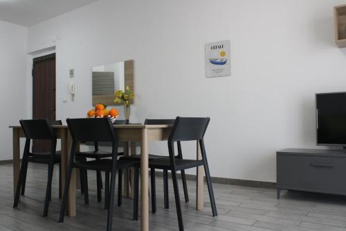 a dining room table with black chairs and a television at Casa Vacanze Etna Sunset in Giarre