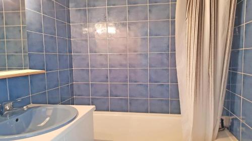 une salle de bain carrelée bleue avec un lavabo et une baignoire dans l'établissement Résidence Pendine 2 - P2302 - Appt T2 - 5 PERSONNES - Pied des pistes MAE-1994, à Les Prés