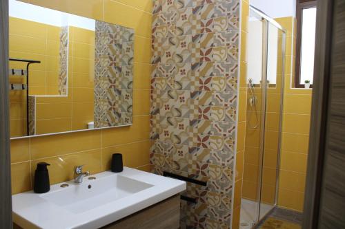 un bagno giallo con lavandino e doccia di Casa Vacanze Etna Sunset a Giarre