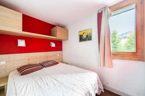 - une chambre dotée d'un lit avec un mur rouge dans l'établissement Résidence Plagne Lauze - maeva Home - Appartement 2 Pièces 5 Personnes - Prestige MAE-0144, à Mâcot La Plagne