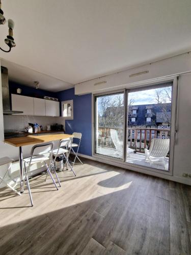 une cuisine et un salon avec une table et des chaises dans l'établissement Appartement charmant bord de mer, à Cabourg