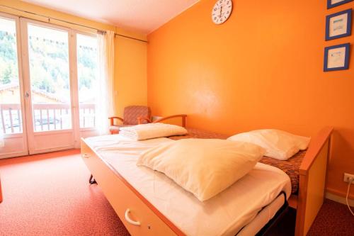 una camera con un letto con una parete arancione di Résidence Le Pra - 2 Pièces pour 4 Personnes 193057 a Villarodin-Bourget