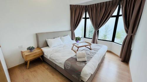 a bedroom with a bed with a table and windows at Mutiara Melaka Beach Resort by Glex in Tangga Batu