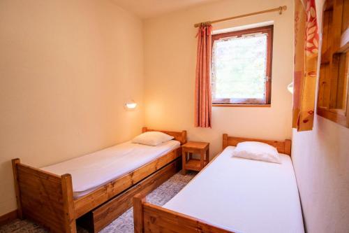 deux lits dans une petite pièce avec une fenêtre dans l'établissement Résidence Les Arolles - LES AROLLES - AR09B MAE-3056, à Villarodin-Bourget