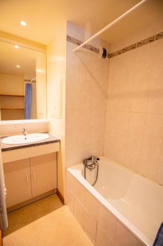 une salle de bain avec une baignoire blanche et un lavabo dans l'établissement Résidence Les Arolles - LES AROLLES - AR09B MAE-3056, à Villarodin-Bourget