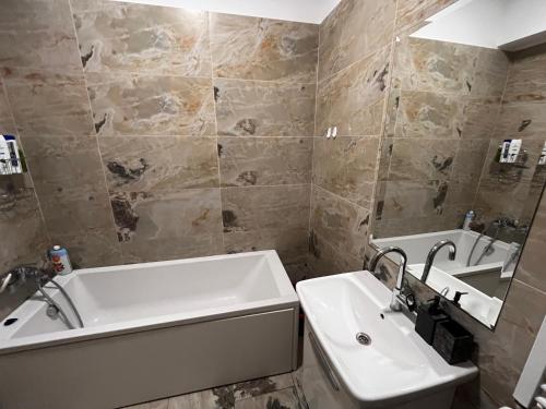 y baño con lavamanos, bañera y lavamanos. en Apartments Lux Palas en Iaşi
