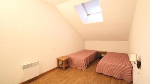 une chambre mansardée avec deux lits et une fenêtre dans l'établissement Résidence Parc Aux Etoiles - B102PAE - APPARTEMENT 3 CHAMBRES, BALCON MAE-2504, à Narreyroux