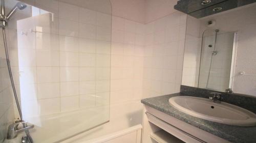 uma casa de banho branca com um lavatório e um chuveiro em Résidence Parc Aux Etoiles - 4 Pièces pour 7 Personnes 504 em Narreyroux