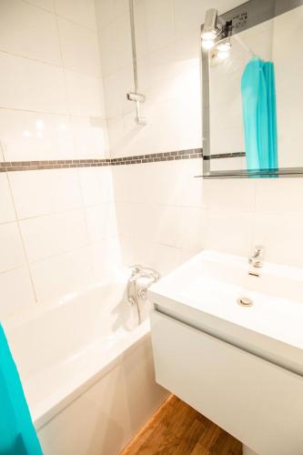 La salle de bains blanche est pourvue d'un lavabo et d'une baignoire. dans l'établissement Résidence Les Campanules - LES CAMPANULES - CA15FC MAE-3064, à Villarodin-Bourget