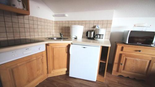 La cuisine est équipée d'un réfrigérateur blanc et d'un four micro-ondes. dans l'établissement Résidence Dame Blanche - DBA420 - APPT 1 CHAMBRE - BALCON - 4 PERSONNES - Secteur 1800 MAE-2624, à Narreyroux