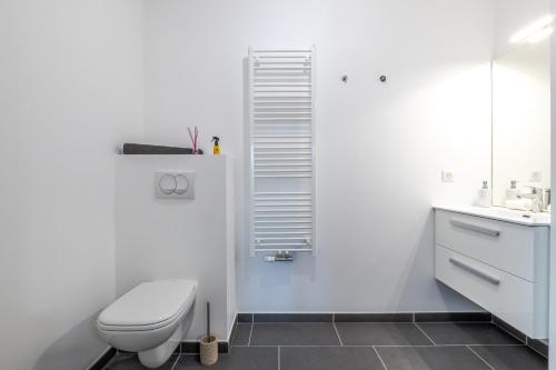 une salle de bain blanche avec des toilettes et un lavabo dans l'établissement Le Petit Paradis vue lac, à Annecy