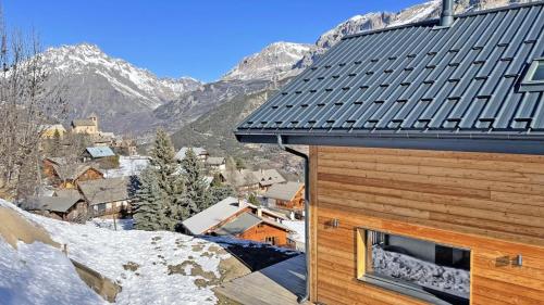 a building with a snow covered roof with mountains in the background at Chalet - Superbe Chalet 12 pers MAE-2644 in Les Prés