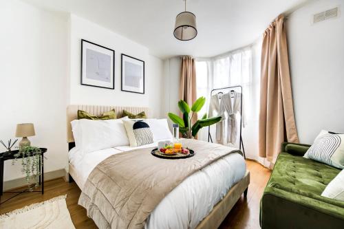 1 dormitorio con 1 cama y 1 sofá verde en Heart of Hackney - 2bed garden flat sleeps 6 en Londres
